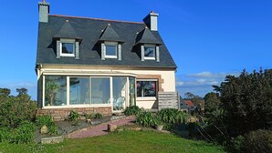 A house with a large front window, a stone foundation, and a sloped roof. - Maison Vue mer avec grand jardin sur la Côte de Granit Rose (Pleumeur-Bodou)