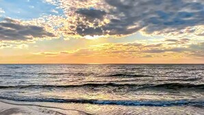 Une plage avec des vagues et un coucher de soleil.