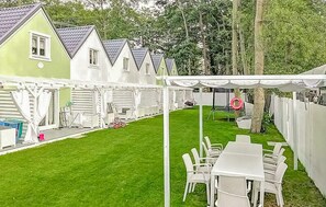 A backyard with a white tent, a grassy lawn, and white chairs. - 2 bedroom nice home in Miedzywodzie (Miedzywodzie)