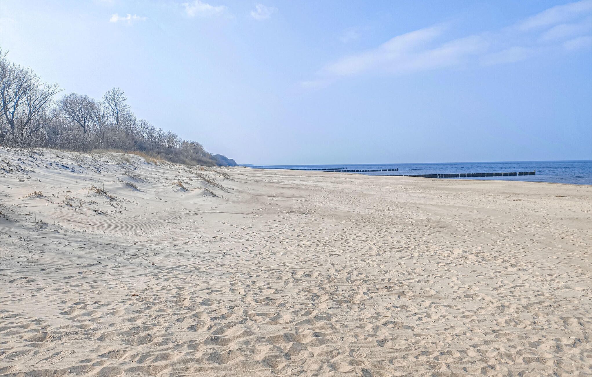 A sandy beach with a clear sky and a distant view of the sea.