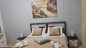 A hotel room with a bed, two bedside tables, a painting on the wall, and towels on the floor.