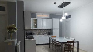 A modern kitchen with white cabinets, a dining table with chairs, and a built-in stove.