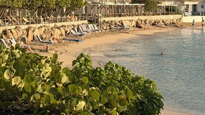 Un hotel frente a la playa con edificios de varios pisos, una playa de arena y un litoral rocoso.