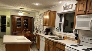A kitchen with wooden cabinets, a central island, a dining area, and a ceiling fan.