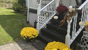 A white house with a porch, a welcome mat, and yellow flowers.