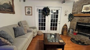 A living room with a sofa, a coffee table, a fireplace, and a door with a wreath.