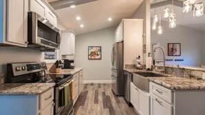 A modern kitchen with stainless steel appliances, granite countertops, and a herringbone wood floor.