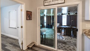 A hallway with a sliding glass door leading to a dining area. A sign above the door reads "Henry's Hideaway Ocala, FL Established 2022."