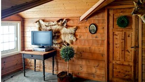 A cozy room with wooden walls, a mounted deer head, a television, and a small plant.
