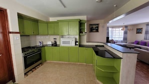 A kitchen with green cabinets, a microwave, a stove, and a sink. - Spacious 3 bedroom with pool (Nairobi)