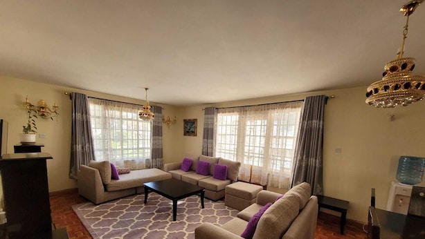 A living room with a sofa set, a coffee table, and a chandelier. - Spacious 3 bedroom with pool (Nairobi)
