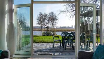 Een moderne kamer met een grote schuifdeur die leidt naar een terras buiten, met een tafel en stoelen.