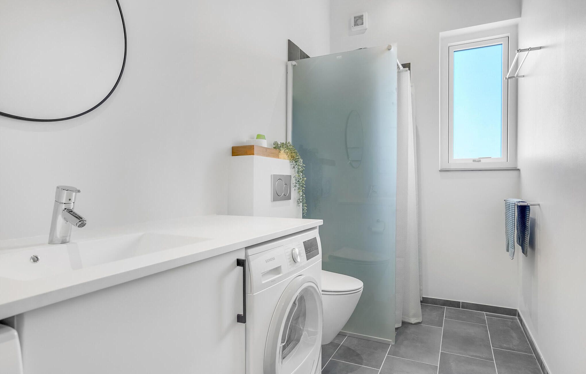 A compact bathroom with a white sink, a toilet, and a washing machine.