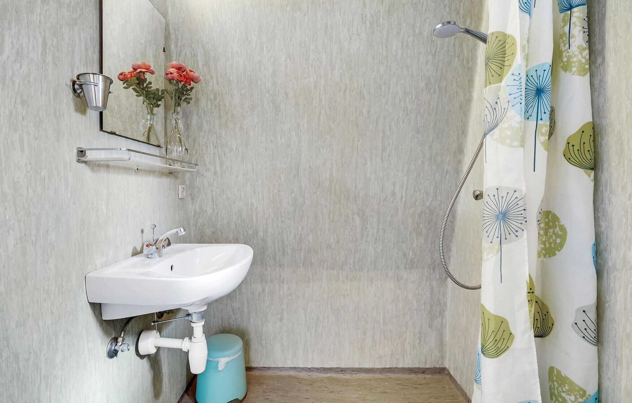 A bathroom with a white sink, a mirror, and a shower curtain with a floral pattern.