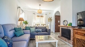 A living room with a sofa, a glass coffee table, a fireplace, and a television.