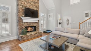 Una sala de estar con chimenea de piedra, un sofá, una mesa de centro y una escalera.
