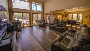 Ein geräumiges Wohnzimmer mit Ledersofas, einem Essbereich und großen Fenstern, die für natürliches Licht sorgen.