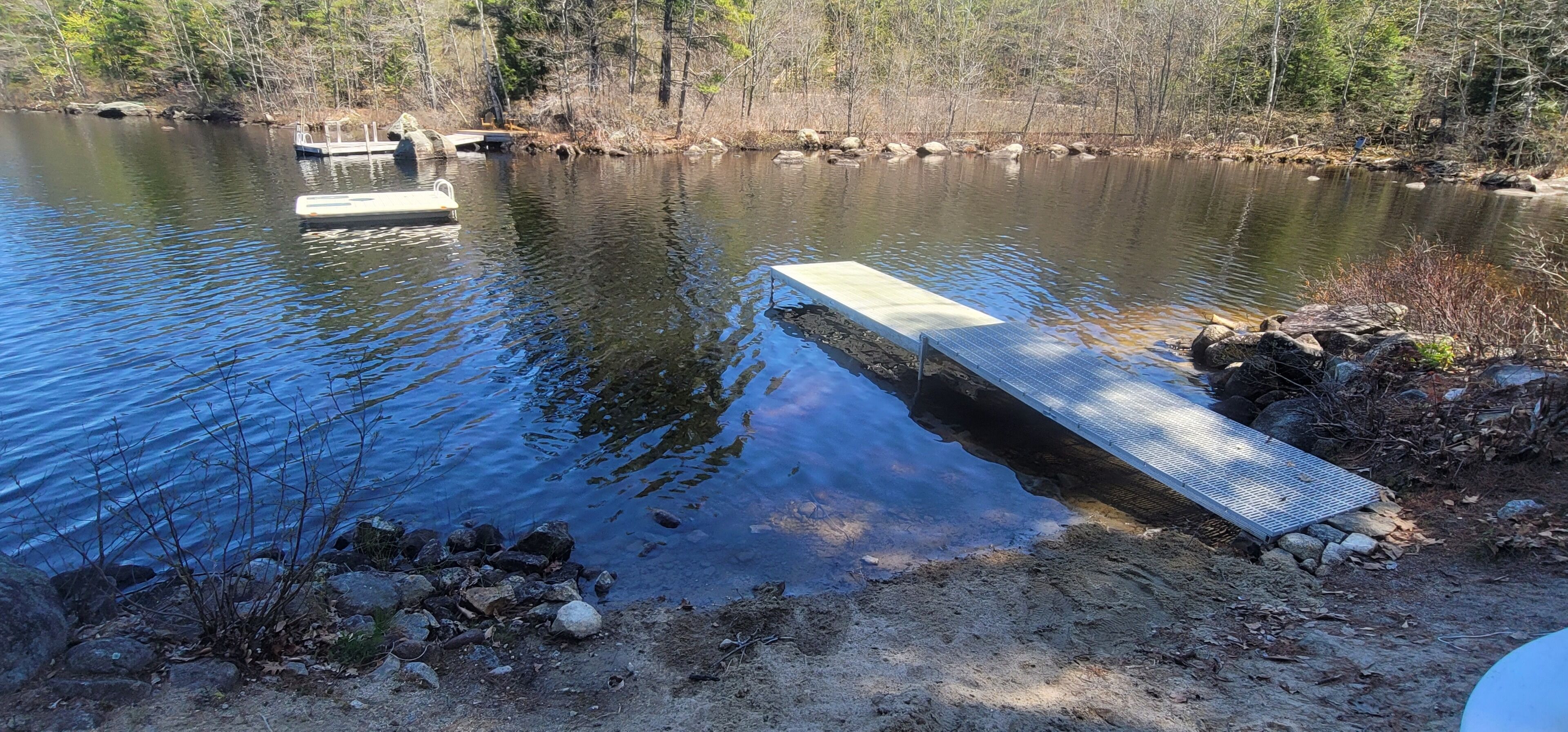 A dock extending into a calm lake surrounded by trees.