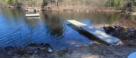 A dock extending into a calm lake surrounded by trees.