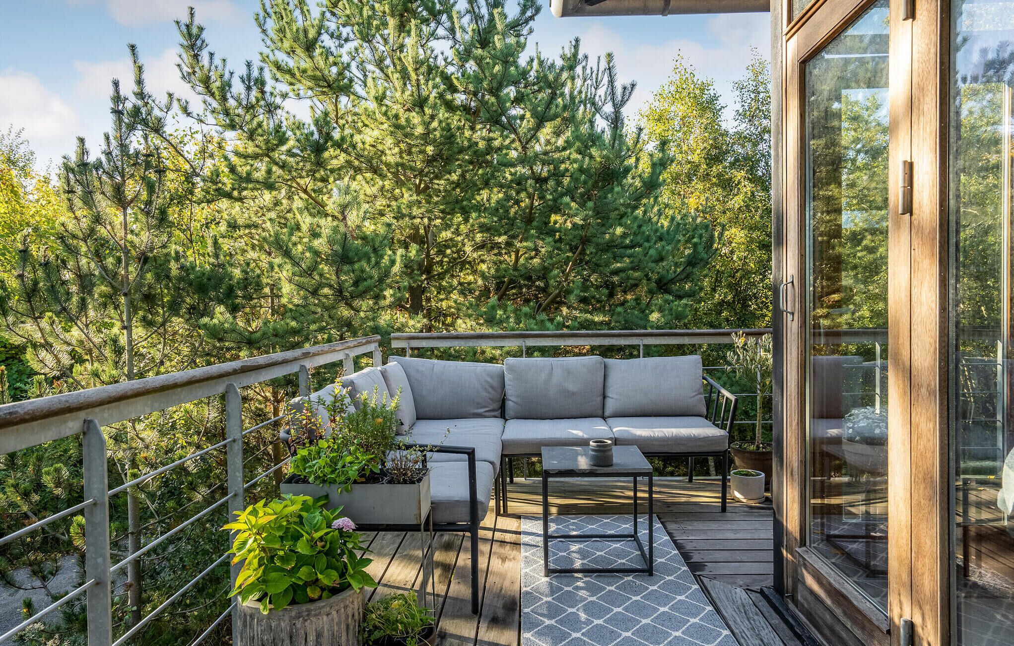 Un balcon avec un canapé, une petite table et des plantes en pot.