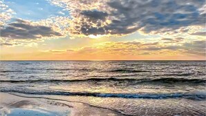 Une plage avec des vagues et un coucher de soleil.