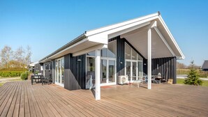 Een modern huis met een ruim terras, schuiframen en een overdekte patio.