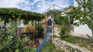 A rustic outdoor area with a wooden bench, a hammock, and a stone wall. - Beautiful home in Marusici (Omis) with WiFi (Marusici (Omis))