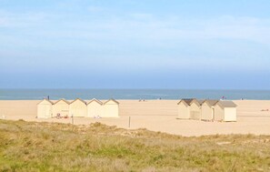 En rad strandhytter på en sandstrand med havet i bakgrunden.