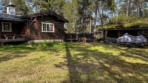 A rustic cabin with a flag, a covered area, and a grassy yard. - Lovely home in Drevsjø with lake view (Engerdal)