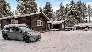 A cabin with a car parked in front, surrounded by snow-covered trees. - Lovely home in Drevsjø with lake view (Engerdal)