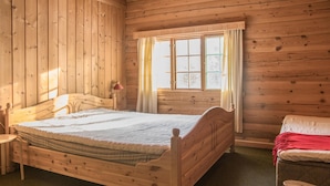 A wooden cabin bedroom with a single bed, a nightstand, a chair, and a window with curtains. - Lovely home in Drevsjø with lake view (Engerdal)
