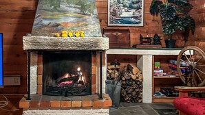 A fireplace with a stone surround, a wooden mantel, and a painting above it. - Lovely home in Drevsjø with lake view (Engerdal)
