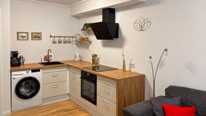 Ett kompakt kök med tvättmaskin, ugn och kaffebryggare.