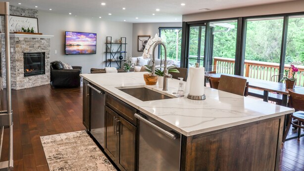 A modern kitchen with a large island, a fireplace, and a dining area with a view of the outdoors.