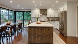A modern kitchen with white cabinets, a stainless steel refrigerator, and a wooden island.