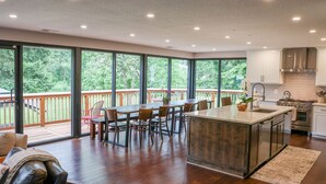 A spacious kitchen with a large island, wooden flooring, and a view of a wooden deck.