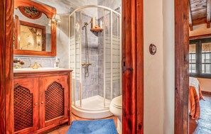 Un baño con tocador de madera, cabina de ducha de vidrio y retrete.