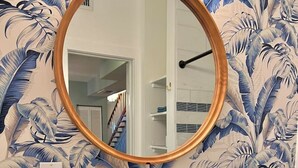 A bathroom with a white sink, a mirror with a wooden frame, a hairdryer, a small potted plant, and a towel.