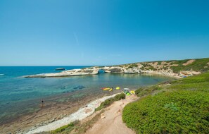 A coastal landscape with clear waters, rocky cliffs, and a sandy beach. - 3 bedroom beautiful home in Milis (Milis)