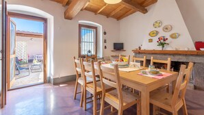 A dining area with a wooden table and chairs, a fireplace, and a TV on a shelf.