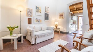 A spacious living room with a white sofa, a coffee table, and a dining area with wooden chairs.