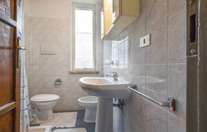 Ein Badezimmer mit Waschbecken, zwei Toiletten, einem Fenster und einem Spiegel.