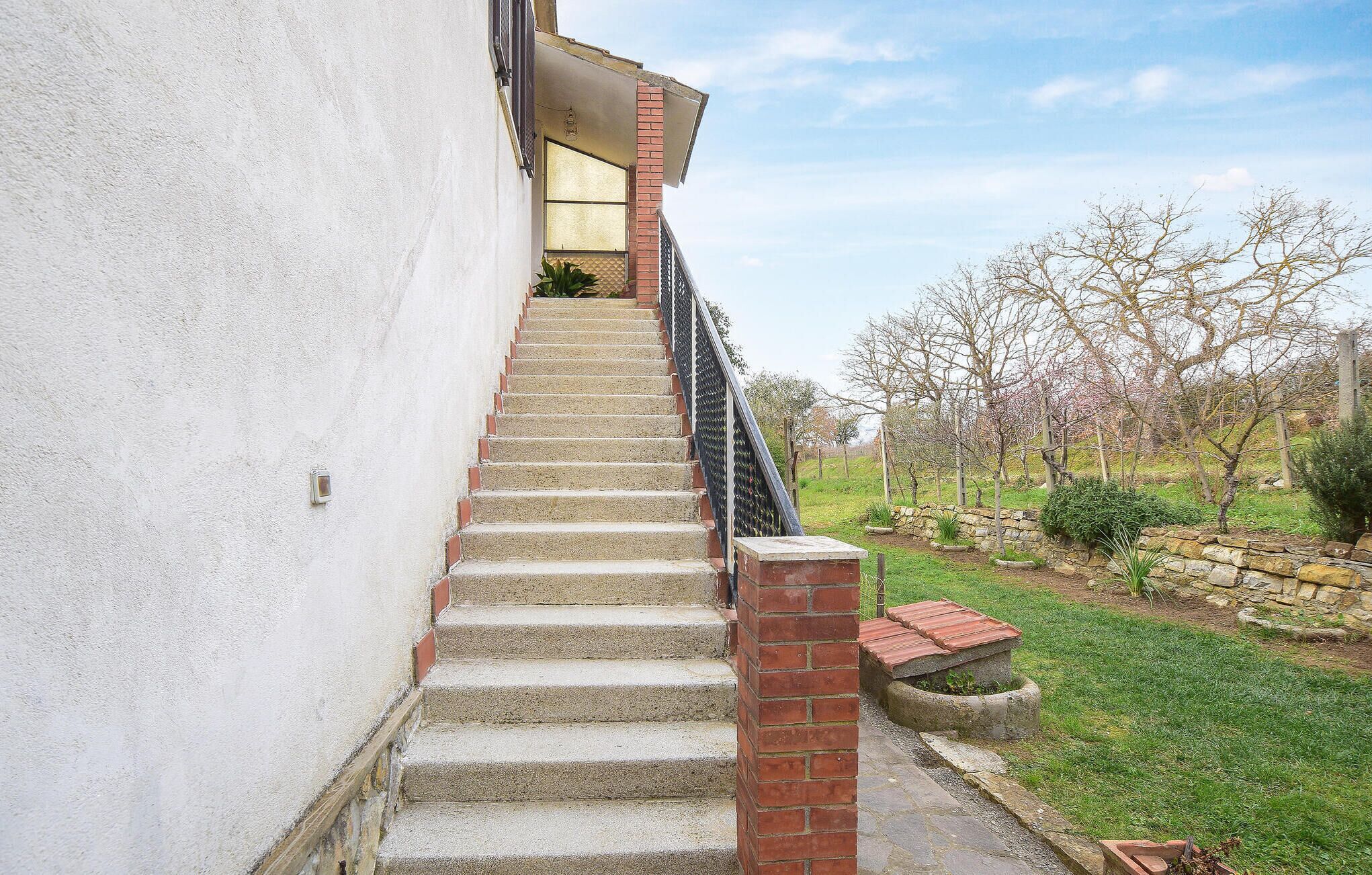 A staircase leading to a building with a white exterior wall and a brick column.