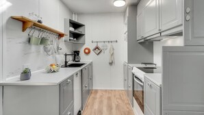 Eine kleine Küche mit weißen Schränken, einer Holz Arbeitsplatte und einem kleinen Fenster.