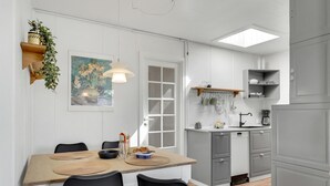 Eine moderne Küche mit Essbereich, ausgestattet mit einem Holztisch, schwarzen Stühlen, einer hängenden Pflanze und einem Bild an der Wand.