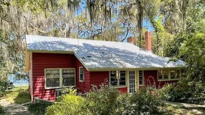 Una casa rossa con tetto in metallo, immersa nel verde e circondata da alberi.