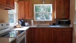 Una cucina con mobili in legno, un forno a microonde, una macchina da caffè, un tostapane e un lavello.