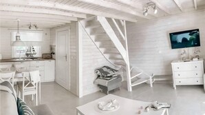 Un intérieur moderne avec un escalier, des meubles blancs et un téléviseur à écran plat.