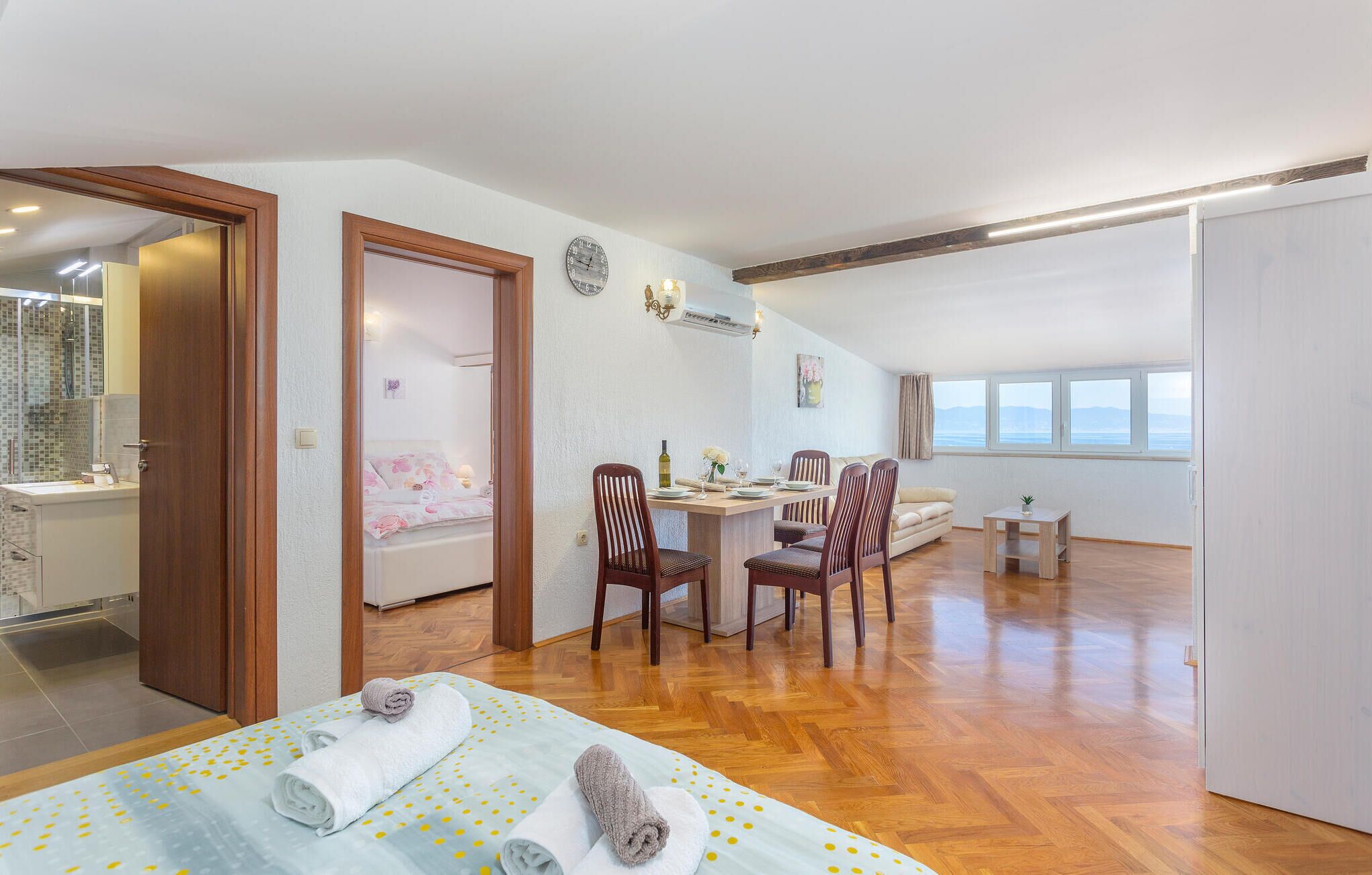 Un dormitorio con cama, escritorio y zona de comedor con sillas.