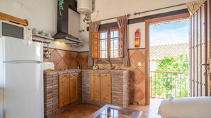 A kitchen with a refrigerator, microwave, and stove. There is a window with curtains, a sink, and a fire extinguisher. - 1 bedroom cozy apartment in Mondron (Mondron)